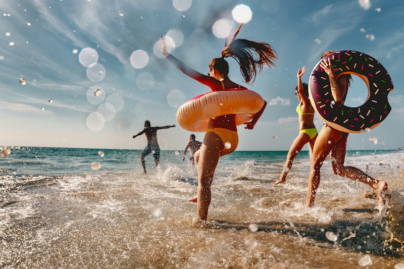 En grupp vänner som springer till sandstranden för att bada